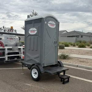 Southwest Sanitation single unit porta potty trailer with entry step, parked beside a Southwest Sanitation service truck in Phoenix