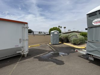 Southwest Sanitation porta potties next to a roll-off dumpster in a Sun City, AZ parking lot